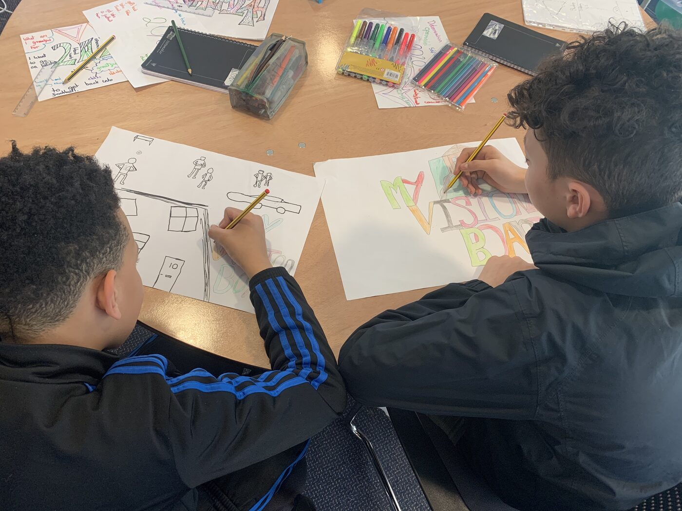 Two young people sketching out ideas on paper during a session
