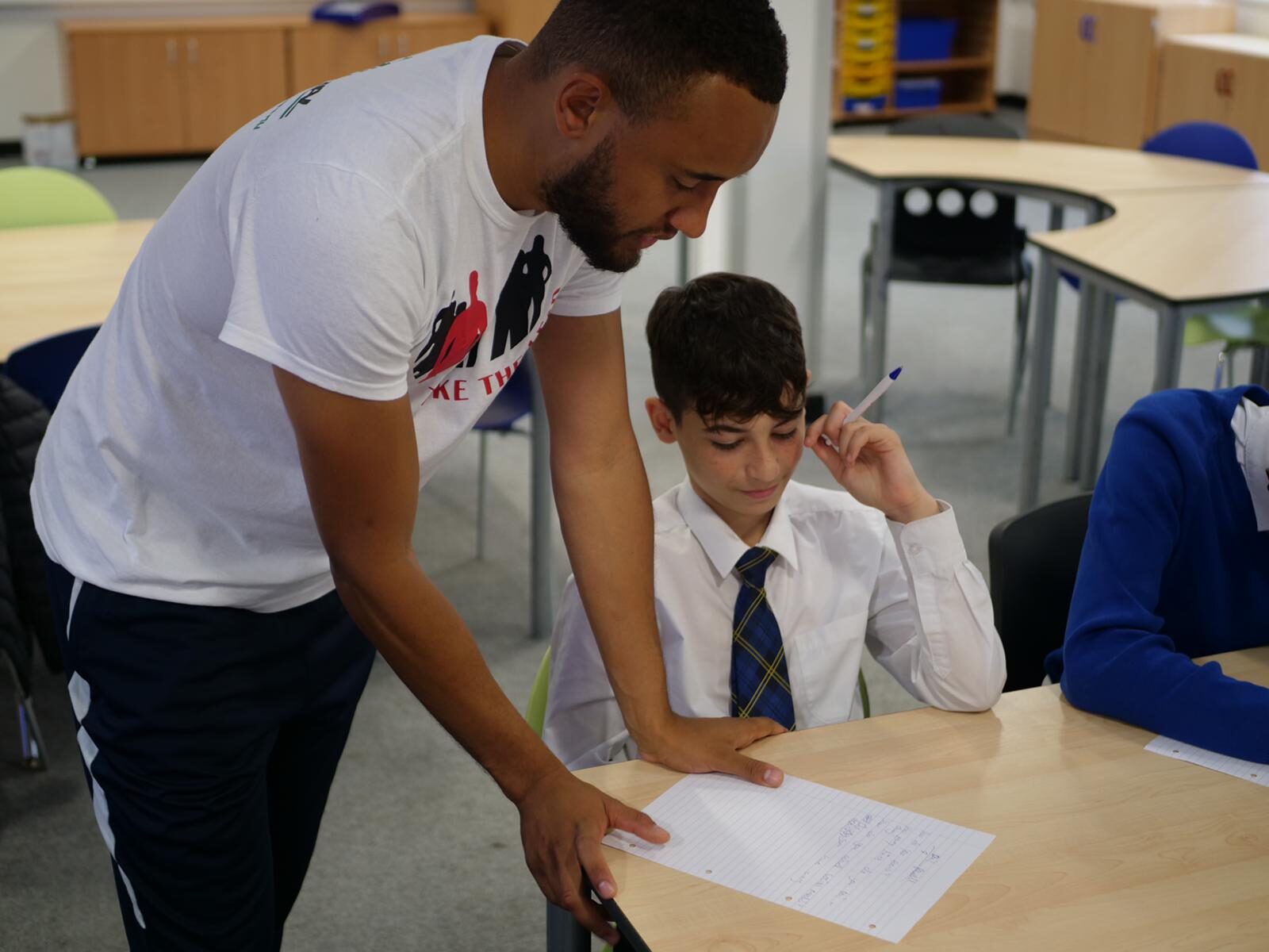 A Directional mentor working one-to-one with a pupil on a piece of writing in school