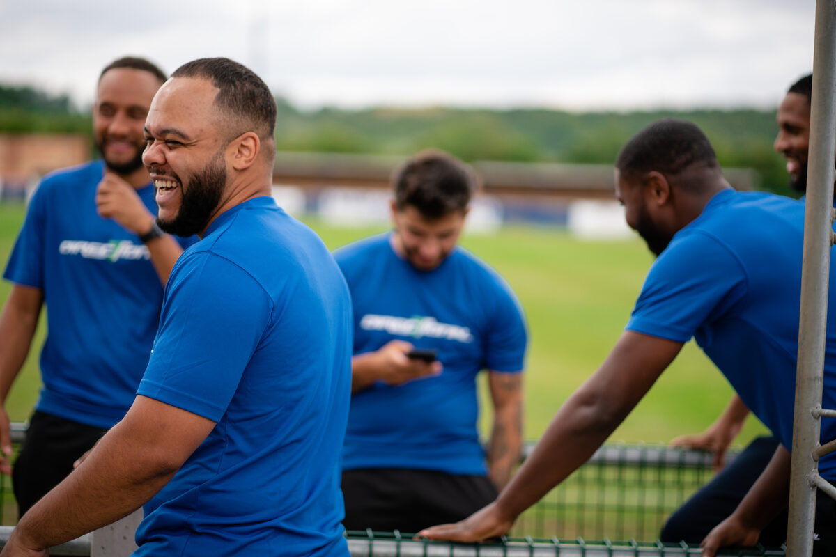 Directional staff sharing a laugh at the side of the pitch